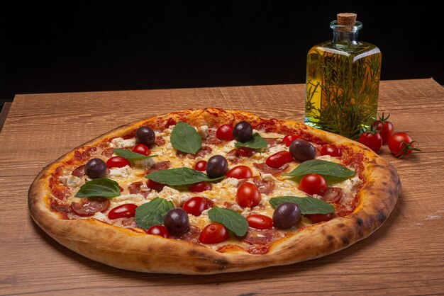 Pizza de mussarela de búfala com tomate cereja fatiado, azeitonas pretas e manjericão na mesa