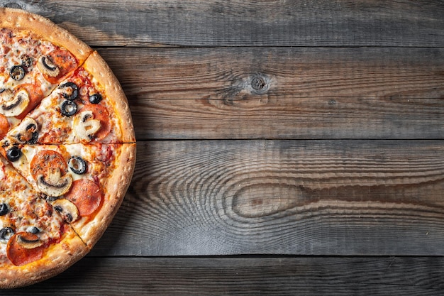 Pizza de pepperoni saborosa com cogumelos e azeitonas em fundo de madeira rústica Vista superior de pizza de pepperon picante Com espaço de cópia para texto
