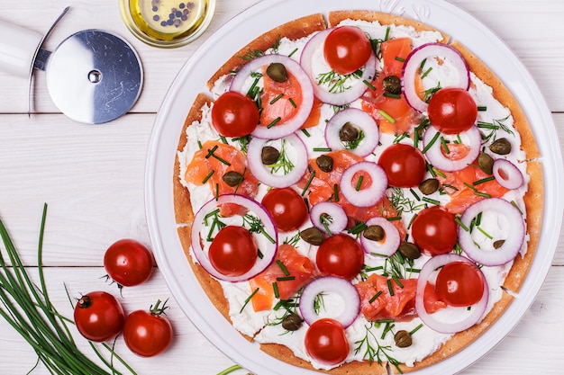 Pizza de salmão escandinava com creme de queijo, alcaparras, tomate e cebola.