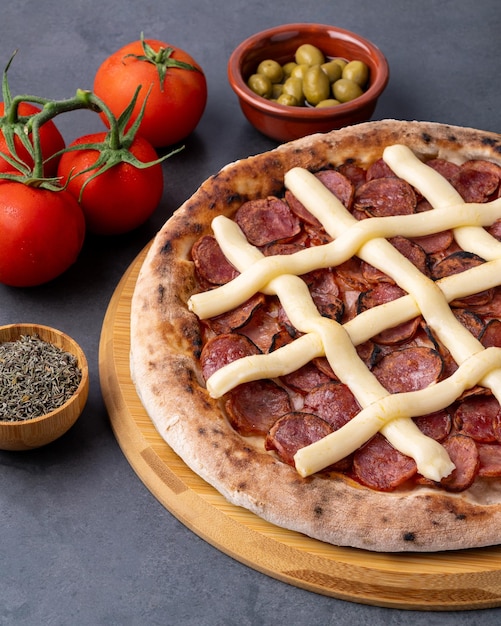 Foto pizza de salsicha de calábria e queijo catupiry sobre fundo de pedra com tomates, azeitonas e orégano