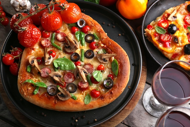 Pizza decorada com legumes em panela em fundo de madeira