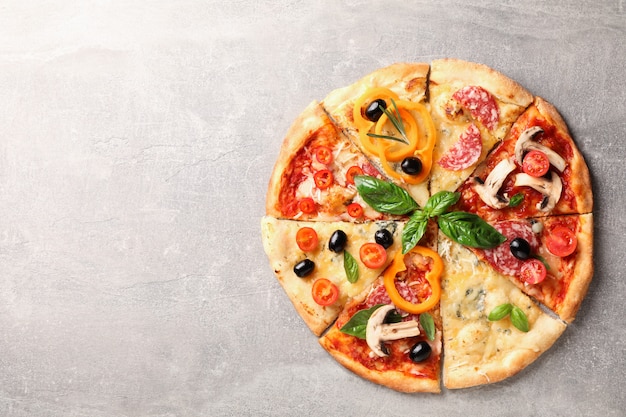 Pizza deliciosa com peças diferentes em fundo cinza