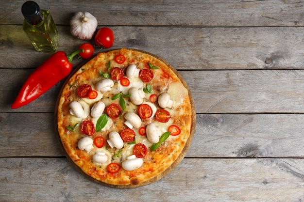 Foto pizza deliciosa e legumes frescos em fundo de madeira fecham