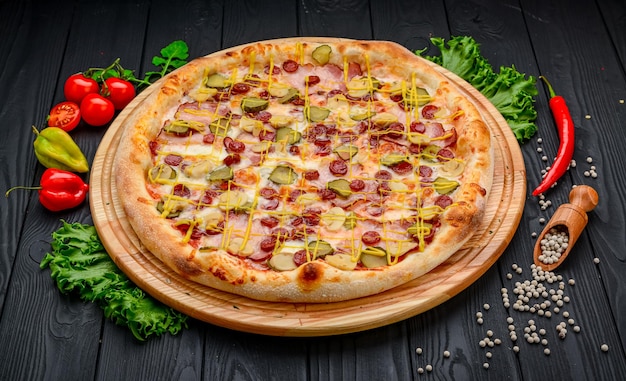 Pizza deliciosa y fresca con salchicha de jamón y pepinos encurtidos