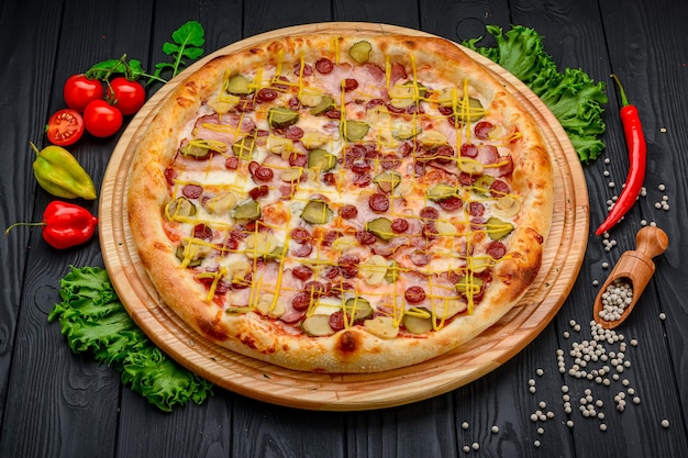 Pizza deliciosa y fresca con salchicha de jamón y pepinos encurtidos