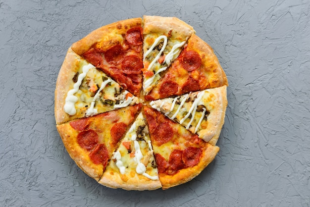 Pizza de diferentes piezas sobre una mesa gris. Orientación horizontal, vista superior, endecha plana.