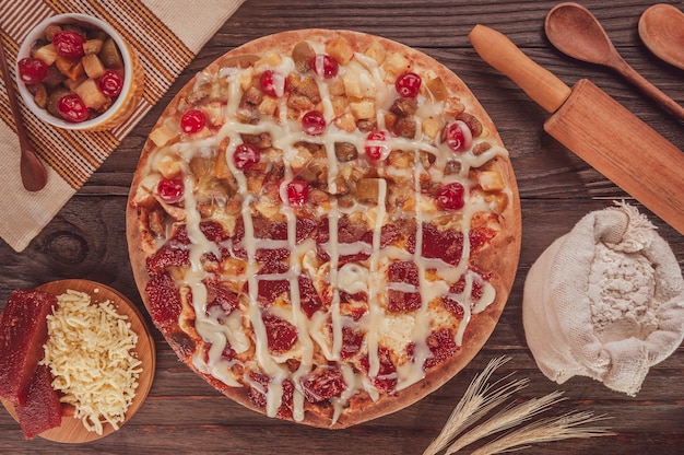 Foto pizza doce brasileira metade fruta em conserva e metade goiabada com queijo e leite condensado. (pizza meio a meio) - vista de cima.