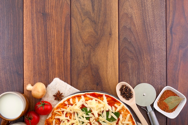 Pizza e ingredientes sobre un fondo de madera