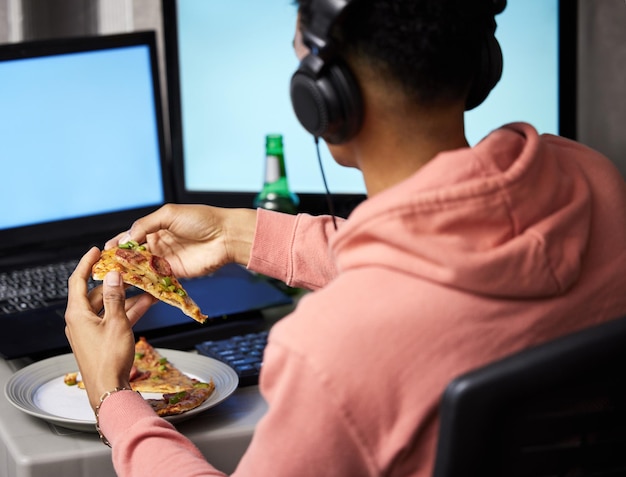 Pizza é uma obrigação durante a noite do jogo. Tiro retrovisor de um jovem comendo pizza enquanto joga videogame em casa.