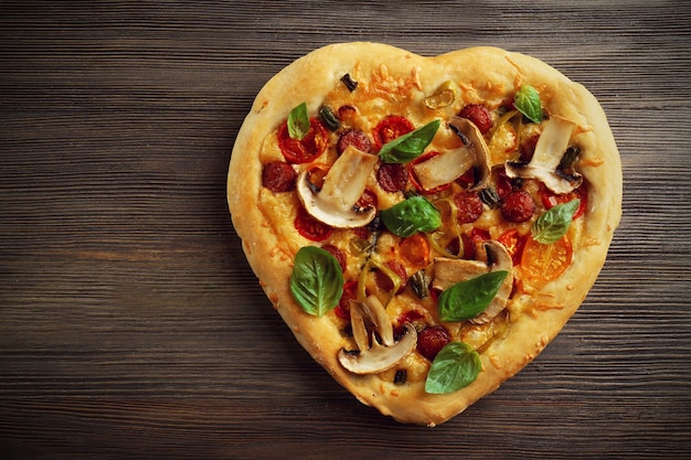 Pizza em forma de coração em fundo de madeira