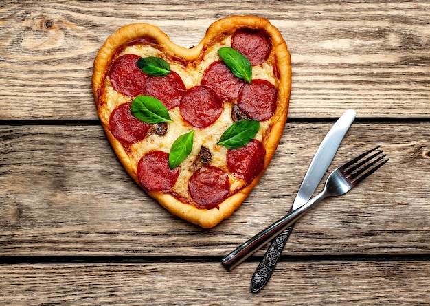 Pizza em forma de coração em uma mesa de madeira