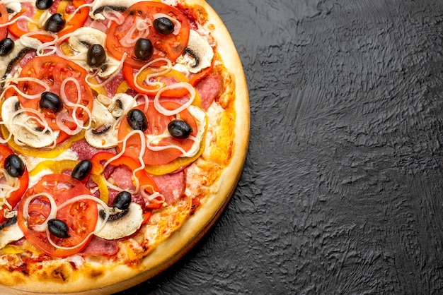 Pizza em fundo preto, à base de tomate com mussarela, presunto, salame, azeitonas, tomate, pimentão, cebola e cogumelos, deliciosa