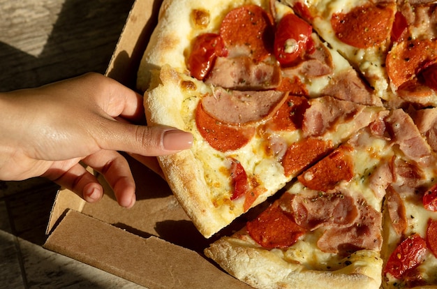 Pizza em uma caixa de papelão em uma lousa escura Vista superior do pacote de pizza Entrega de pizza