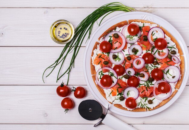 Pizza escandinava de salmón con queso crema, alcaparras, tomate y cebolla.