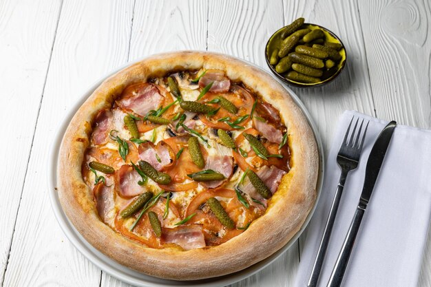 Una pizza con espárragos junto a un tenedor y un cuchillo.