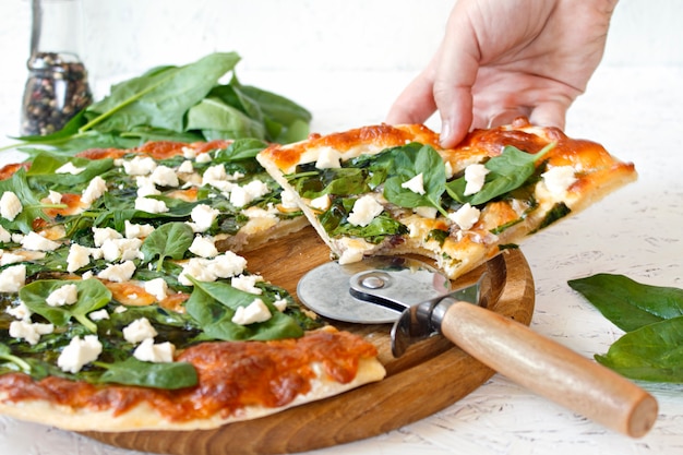 Pizza con espinacas en tablero de madera