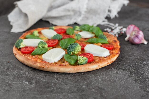 Pizza, Essen, Gemüse. Gemüse-, Pilz- und Tomatenpizza auf einem dunklen Hintergrund