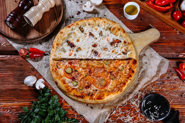 La pizza está en la mesa de la cocina y los ingredientes están esparcidos