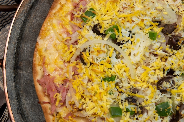 Foto pizza estilo portugués brasileño con jamón, huevo, pimiento, cebolla, mozzarella, vista superior