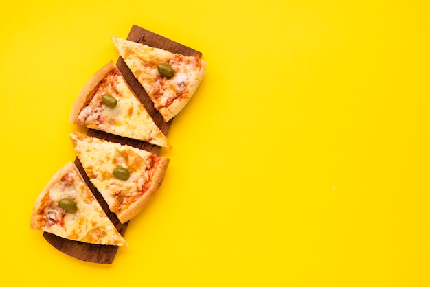 Foto pizza fatia disposta na placa de madeira sobre fundo amarelo