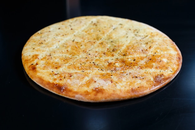 Pizza fatiada em um fundo de pedra preta, vista superior. focaccia recém-assada com queijo