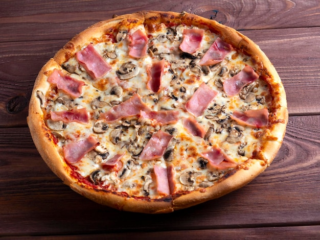 Pizza fechada com presunto e cogumelos sobre fundo de madeira marrom Um prato tradicional italiano Vista superior plana