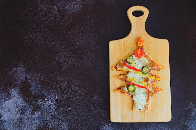 Pizza en forma de árbol de Navidad con queso de tomates sobre fondo negro Mock up plano de espacio de copia