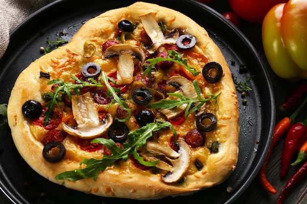 Pizza en forma de corazón en bandeja de metal sobre fondo de madera