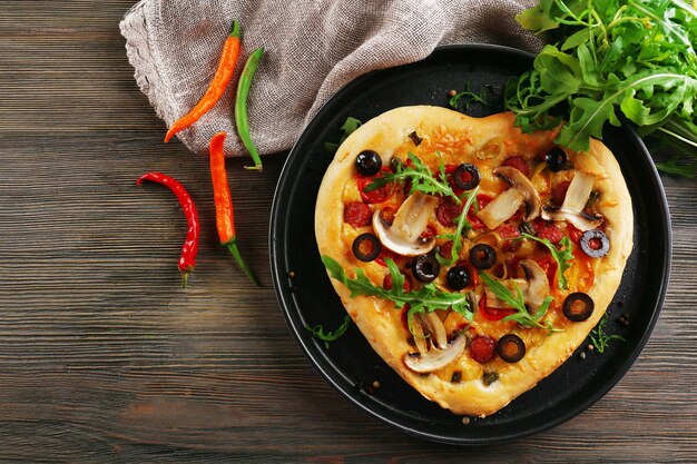 Pizza en forma de corazón en bandeja de metal sobre fondo de madera