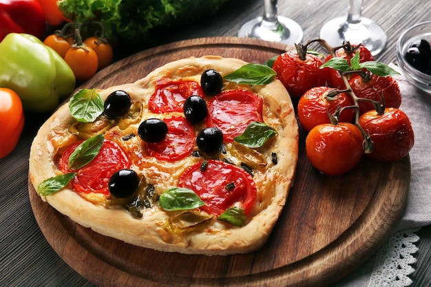 Pizza en forma de corazón servida con vino en mesa de madera