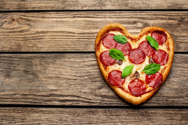 Pizza en forma de corazón sobre una mesa de madera