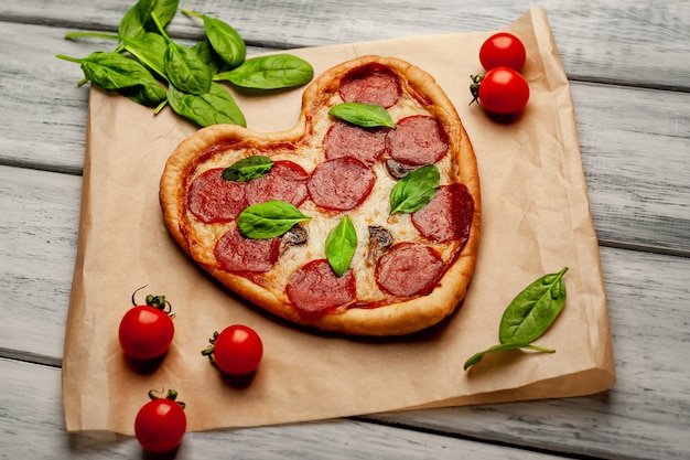 Pizza en forma de corazón sobre una mesa de madera