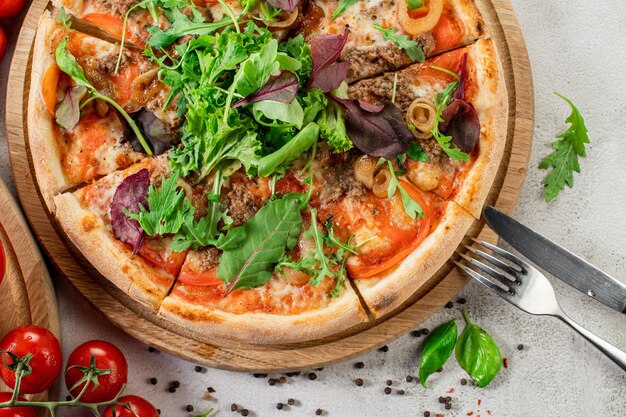 Pizza fresca con carne y verduras en el fondo de hormigón