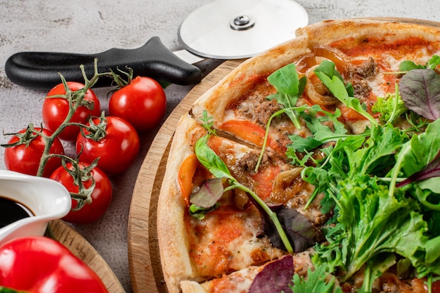 Pizza fresca con carne y verduras en el fondo de hormigón