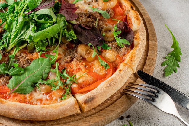 Pizza fresca com carne e legumes no fundo branco de concreto