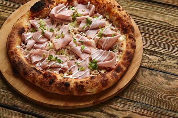 Pizza fresca com presunto e abacaxi na mesa de madeira no restaurante