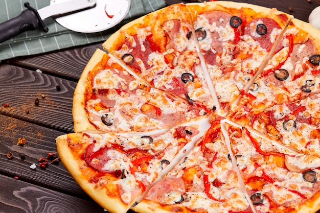 Pizza fresca com tomate, queijo e cogumelos na mesa de madeira closeup.