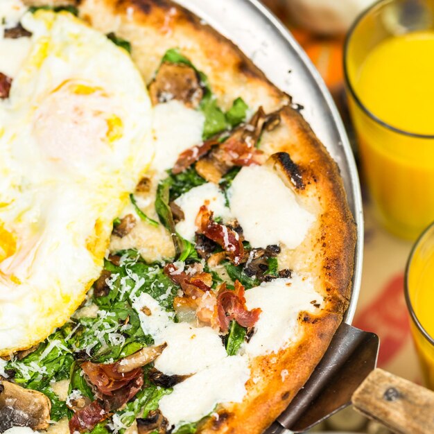 Pizza fresca de desayuno con tres huevos frescos de granja en un restaurante italiano.