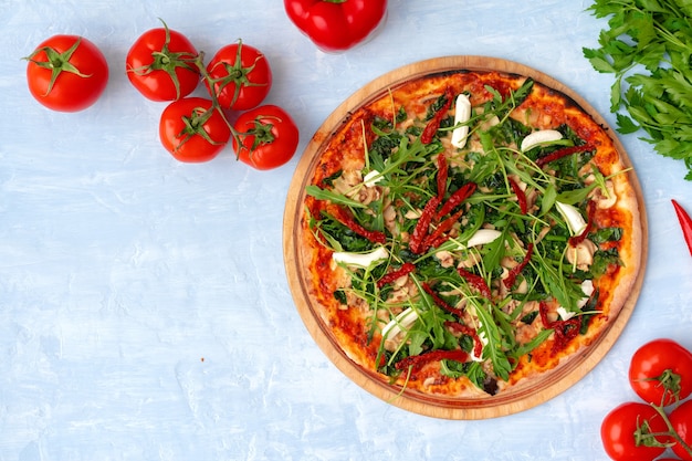 Pizza fresca con hierbas y tomates secados al sol en la vista superior de la mesa gris