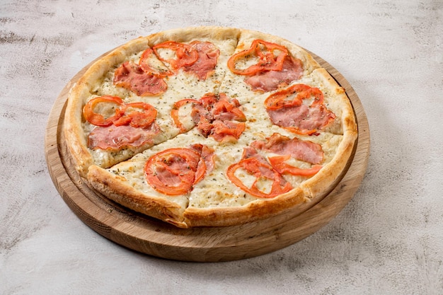 Pizza fresca y sabrosa con salchichas de carne salamy y jamón sobre fondo de hormigón blanco