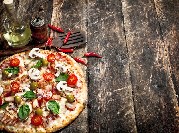 Pizza fresca con tomate en mesa de madera.