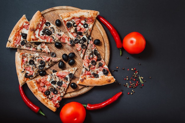 Pizza gefüllt mit Tomaten, rotem Pfeffer, Salami und Oliven