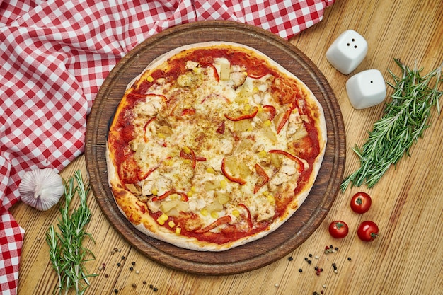 Pizza havaiana com queijo derretido, abacaxi, frango, milho na bandeja de madeira. Pizza em composição com ingredientes na mesa de madeira.