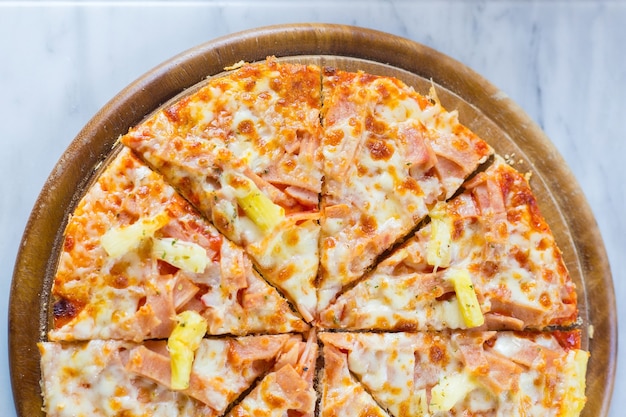 La pizza hawaiana es una comida italiana que se elabora con salsa de tomate, piña picada, jamón y queso.