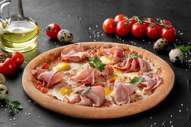 Pizza con huevos de codorniz y jamón sobre superficie negra