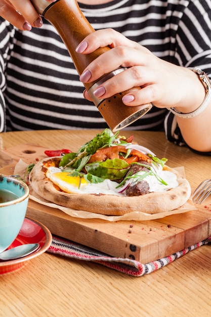 Pizza con huevos, salchichas y hierbas.