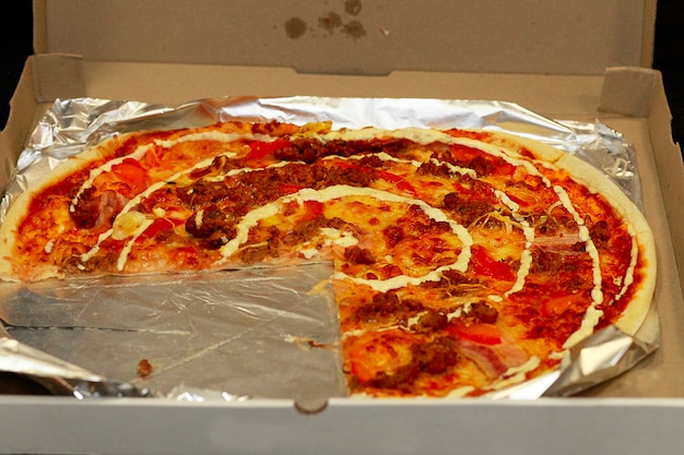 Pizza in einer Schachtel mit einem gebrochenen Stück. Pizza aus dem Café. Pizza. Die übliche Standardpizza.