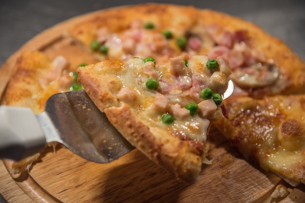 Pizza ist ein italienisches Essen, das auf hölzernem Kreisbrett gedient wird