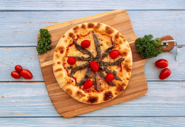 Pizza italiana de anchoas y tomates con vista superior de la mesa de madera