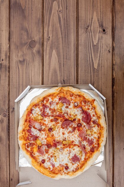 Pizza italiana en caja de cartón sobre mesa de madera